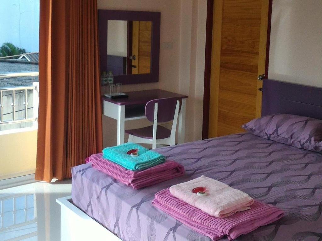a bedroom with towels on a bed with a table at V-House Hotel in Trang