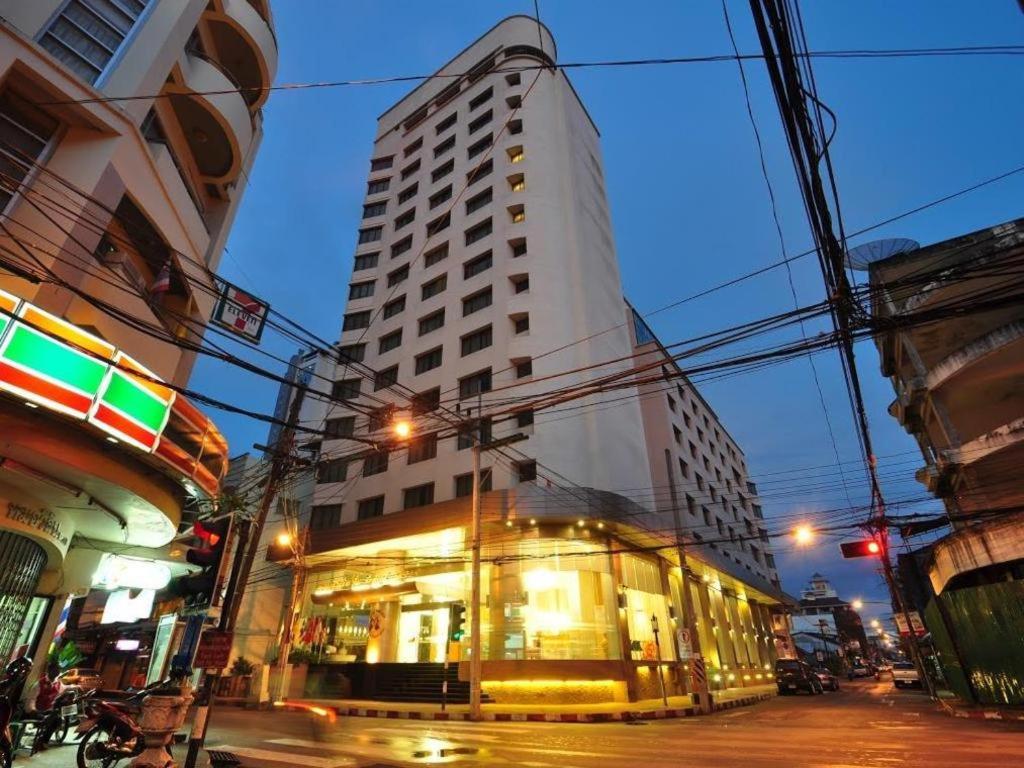 een hoog wit gebouw in een stadsstraat 's nachts bij Mayflower Grande Hotel in Hat Yai