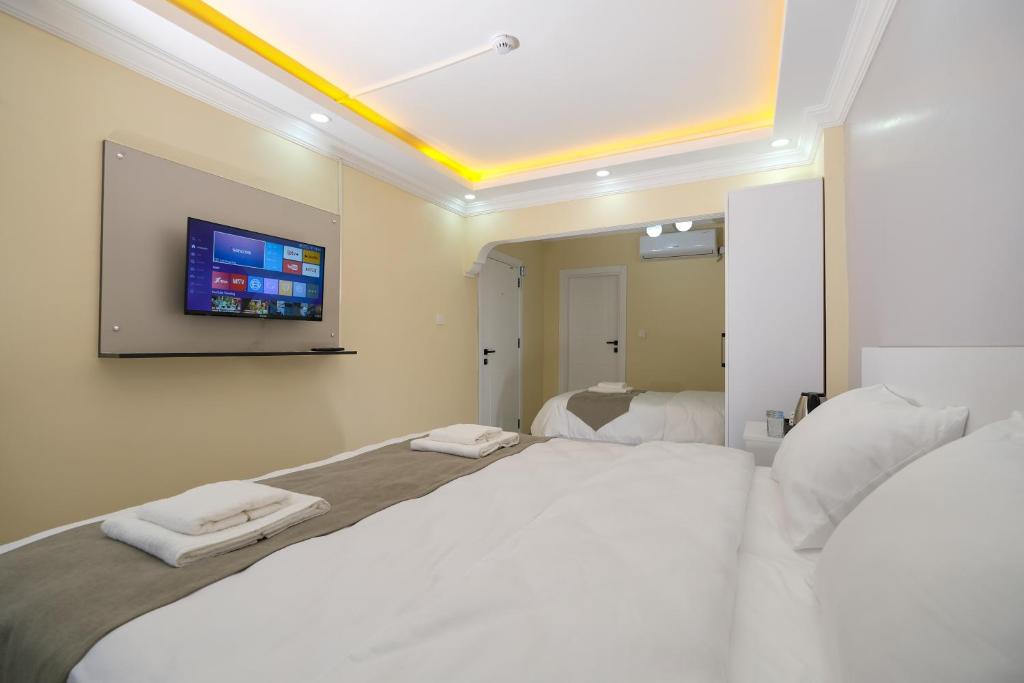 Lucky Hotel İstanbul في إسطنبول: غرفة نوم مع سرير كبير وتلفزيون على الحائط
