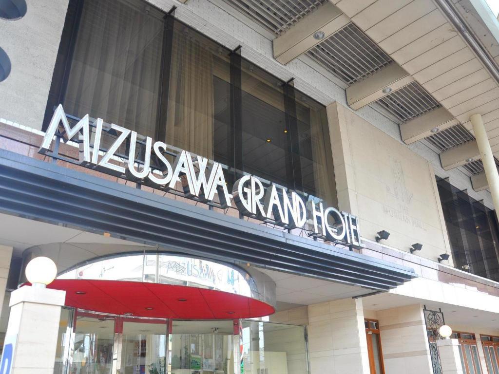 Mizusawa Grand Hotel في Oshu: لافتة فندق فخمة على جانب المبنى