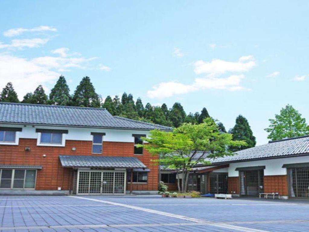 ein rotes Backsteingebäude mit Bäumen im Hintergrund in der Unterkunft Otaiko Hills in Ito
