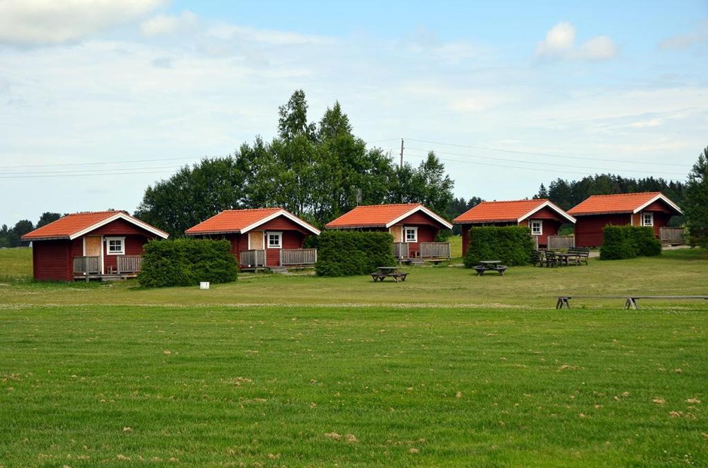una fila de cabañas con techos rojos en un campo en Åbyggeby Landsbygdscenter en Ockelbo