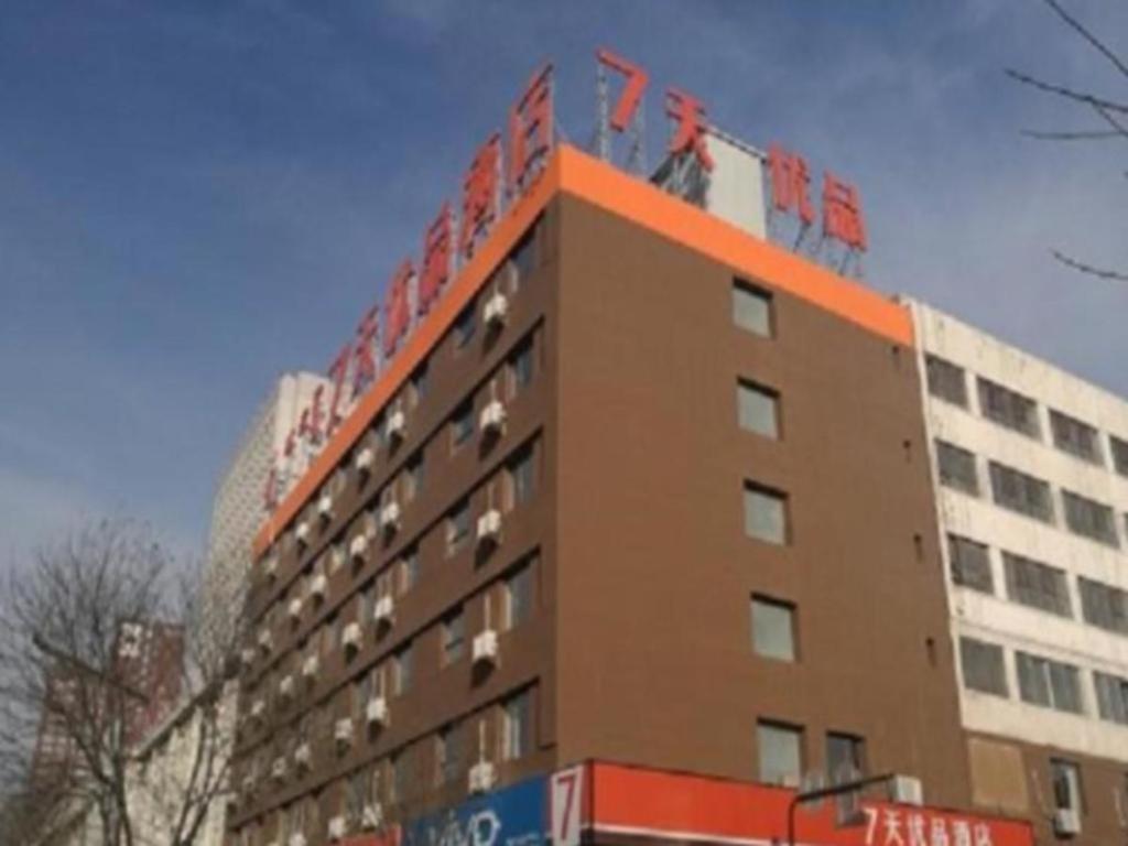 ein hohes Gebäude mit orangefarbenem Dach und einem Gebäude in der Unterkunft 7 Days Premium Hohhot Hailiang Square in Hohhot