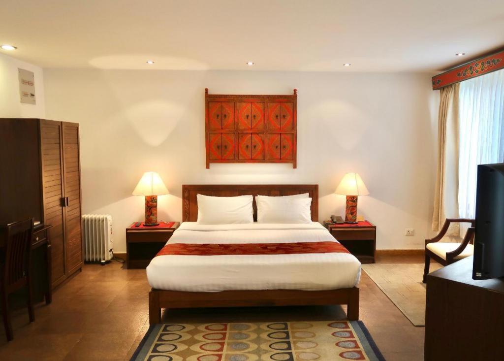 a bedroom with a bed and two lamps and a television at Khang Residency Thimphu in Thimphu