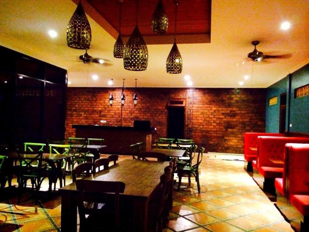 um restaurante com mesas e cadeiras e uma parede de tijolos em Nina Hotel em Salatiga