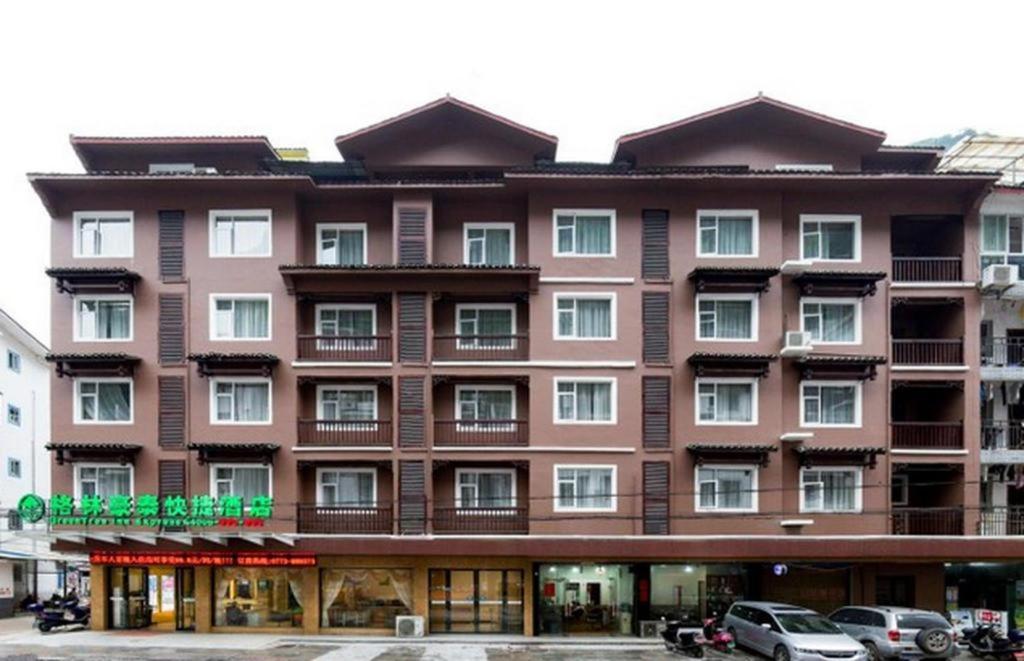 陽朔にあるGreenTree Inn Yangshuo West Street Express Hotelの車が目の前に停まった茶色の大きな建物