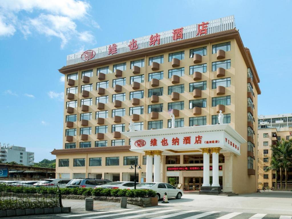 深圳的住宿－Vienna Hotel Shenzhen Yantian Port Branch，一座大型酒店建筑,上面有标志