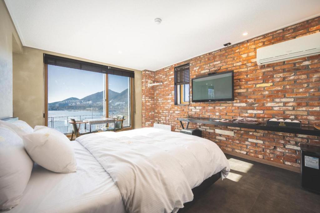 um quarto com uma cama grande e uma parede de tijolos em B&F Hotel em Yeosu