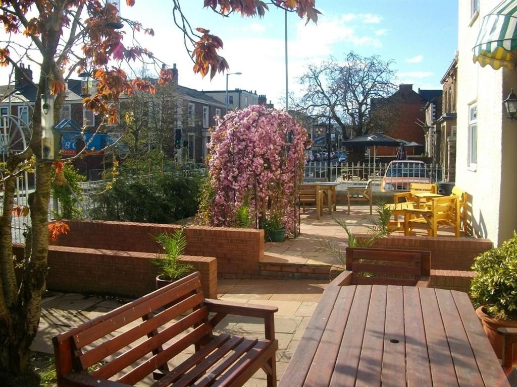 a patio with benches and flowers and tables at Arkale Lodge in Carlisle