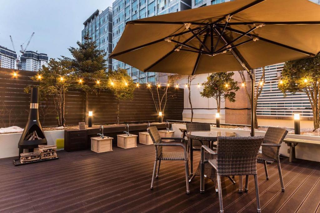 a patio with a table and chairs and an umbrella at Kobos Hotel in Bucheon