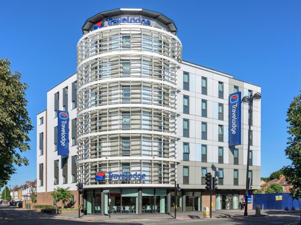 a tall white building with blue signs on it at Travelodge London Hounslow in Hounslow