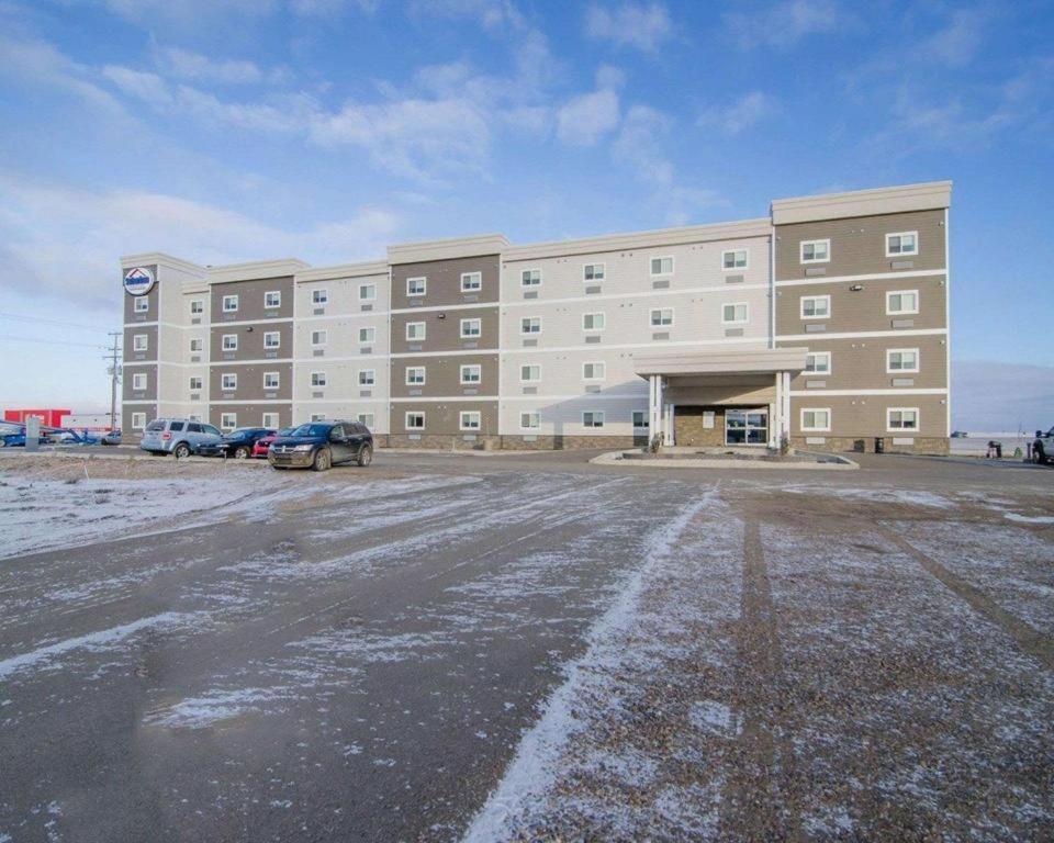 a large building with cars parked in a parking lot at Quality Inn and Suites - KindersLey in Kindersley