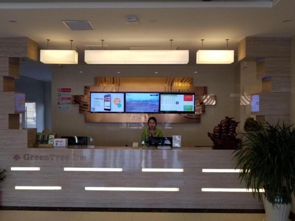 Eine Frau, die an einem Tresen in einem Restaurant sitzt. in der Unterkunft GreenTree Inn Heze Changcheng Road Tianhua E-commerce Logistics Park Express Hotel in Pangwangzhuang