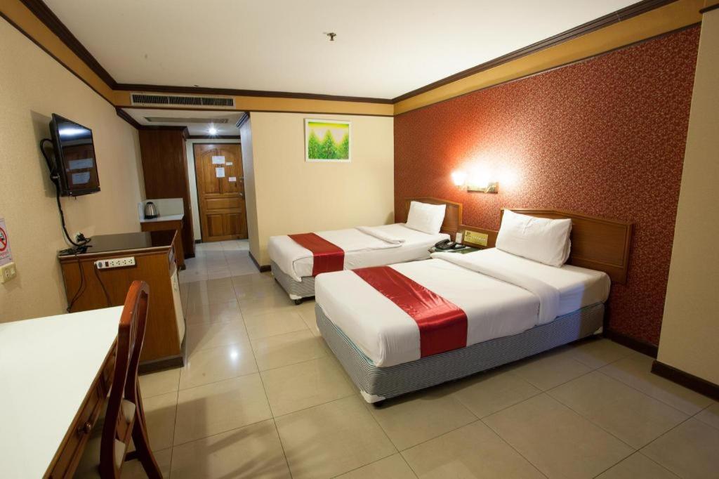 a hotel room with two beds and a television at Aurora Bay Hotel in Bangna