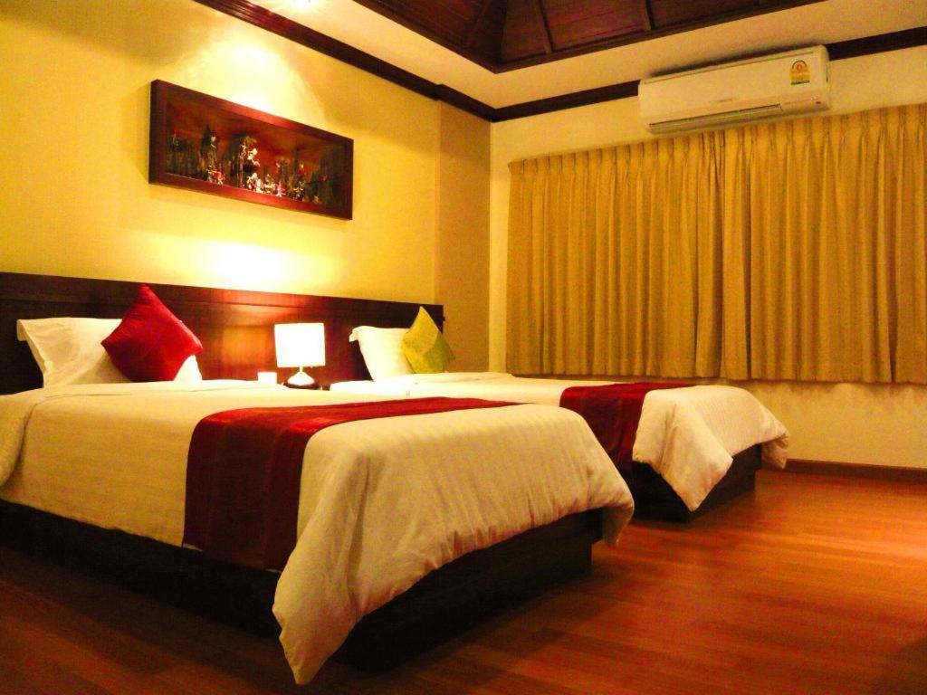 een hotelkamer met 2 bedden en een raam bij King Hotel in Loei
