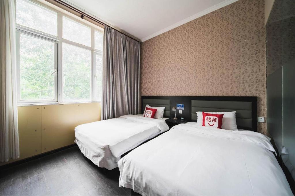 two beds in a room with two windows at PAI Hotel Beijing Capital International Airport Linhe Development Zone in Tahe