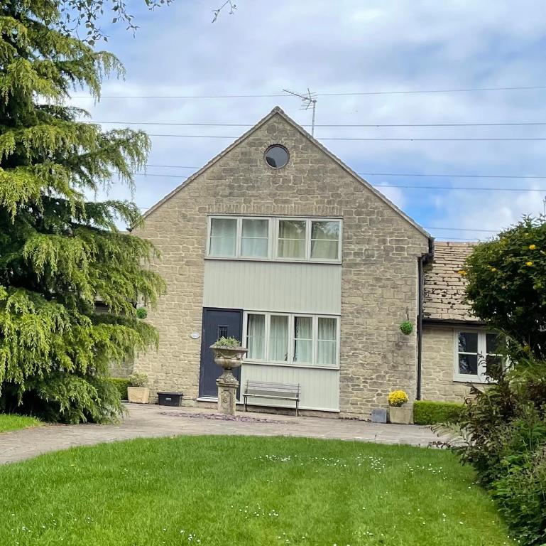 a brick house with a bench in front of it at Sherbourne Cottage, Seven Springs Cottages in Cheltenham