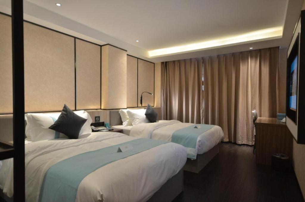 a hotel room with two beds and a flat screen tv at Xana Lite Ganzi Luding YanAn Road in Lutingkiao