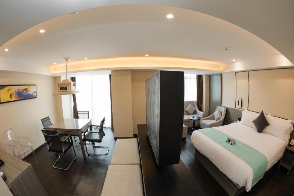 ein Schlafzimmer mit einem Bett und ein Wohnzimmer mit einem Tisch in der Unterkunft Xana Hotelle Nanchang Gaoxin Xincheng Wuyue Plaza in Nanchang