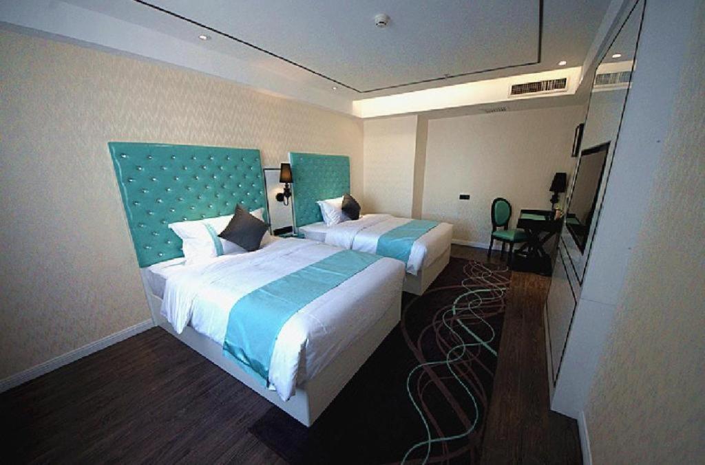 a hotel room with two beds and a desk at Xana Lite Korla Xiangli Avenue Food Street in Korla