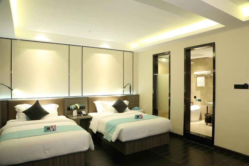 a hotel room with two beds and a bathroom at Xana Lite Jiangmen Yingbin West in Jiangmen
