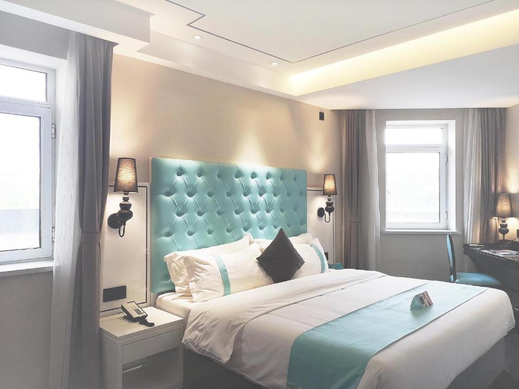 1 dormitorio con 1 cama grande y cabecero azul en Xana Lite Shenyang Beiling Park Liaoning Building Branch, en Shenyang