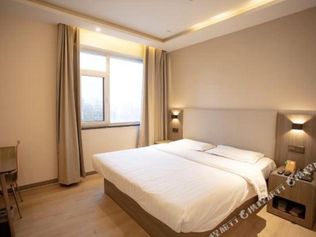 Un dormitorio con una gran cama blanca y una ventana en 7 Days Inn Tianjin Binhai Passenger Station Huabei Ceramics en Binhai