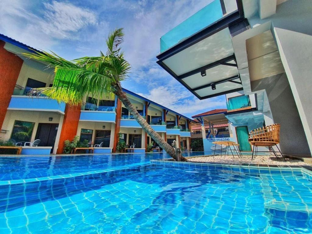 a swimming pool with a palm tree next to a building at The Bed Vacation Rajamangala Hotel in Songkhla