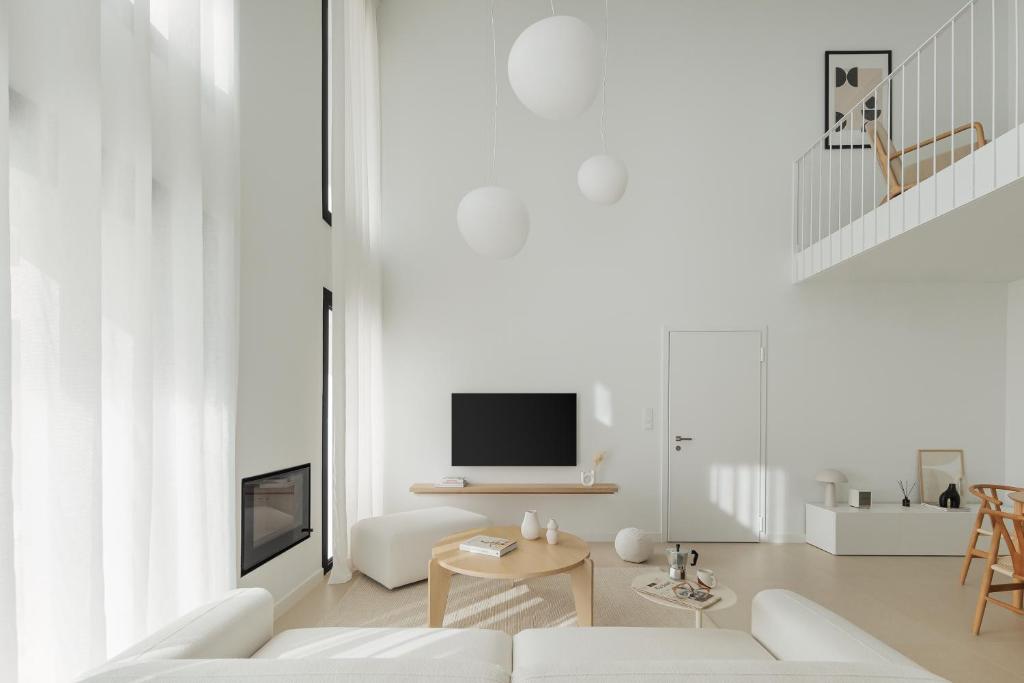 a white living room with a white couch and a tv at Blanc Residences in Ioannina