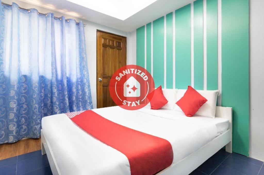 OYO 128 d'Builders Rooms Phase 2 في مانيلا: غرفة نوم بسرير ومخدات حمراء وبيضاء