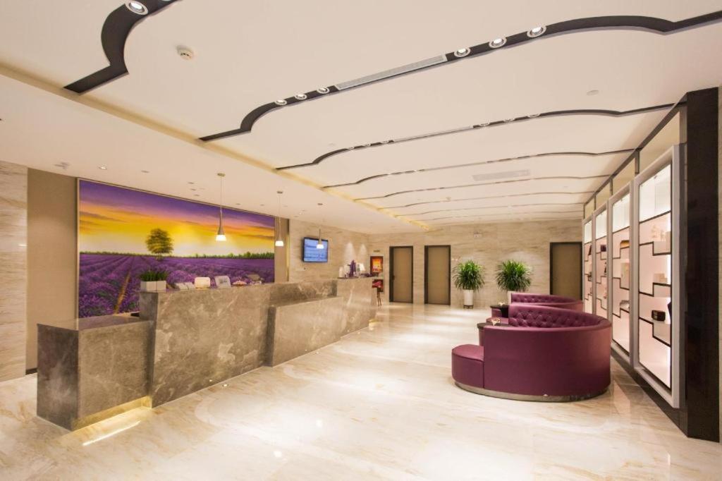 a lobby with purple furniture and a painting on the wall at Lavande Hotels Urumqi Xinmin West Street Hongda Plaza in Ürümqi