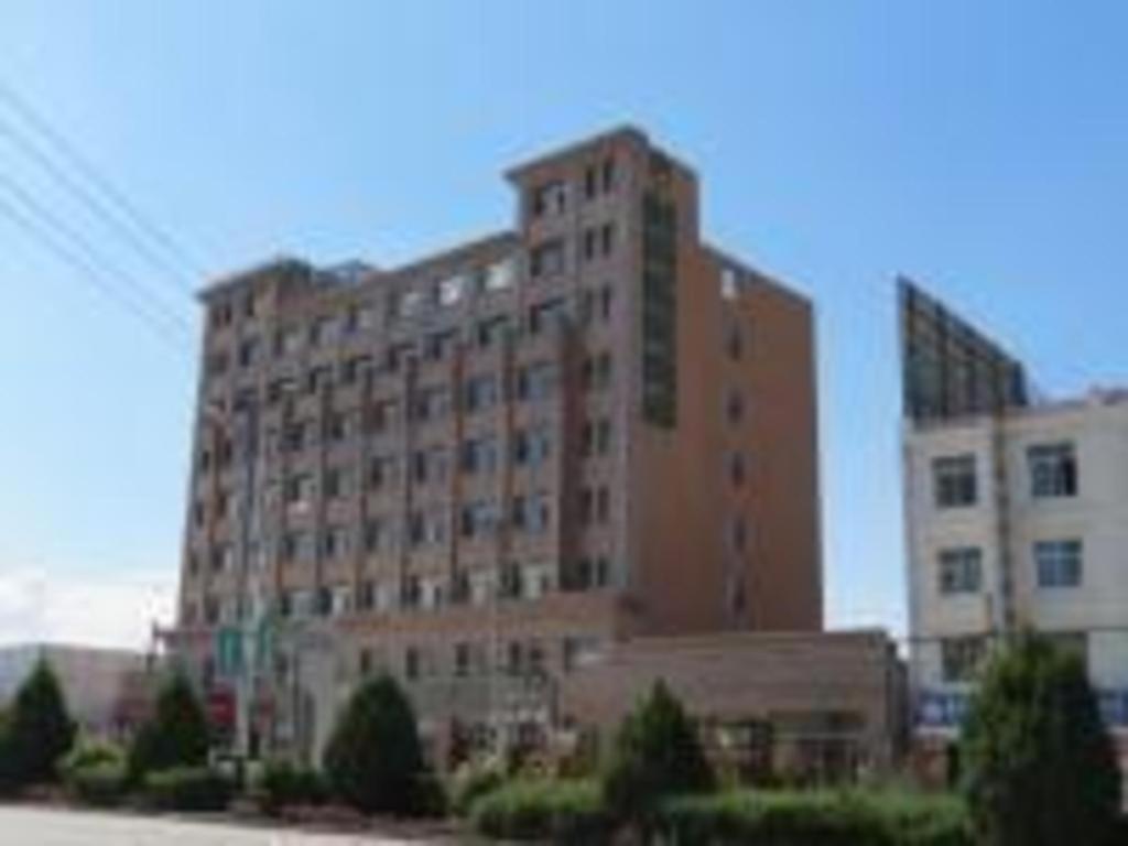 ein großes braunes Gebäude mit vielen Fenstern auf einer Straße in der Unterkunft GreenTree Inn Zhangye Ganzhou Train Station Orthopaedic Hospital in Zhangye