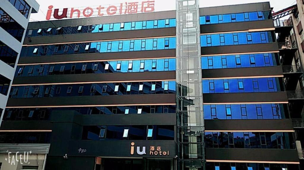 a tall building with blue windows in a city at IU Hotel Kunming Jinma Bijifang Joy City in Kunming