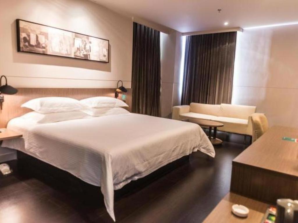 フフホト市にあるJinjiang Inn Select Hohhot Chengjisihan Square Metro Stationのベッドルーム(大きな白いベッド1台、ソファ付)