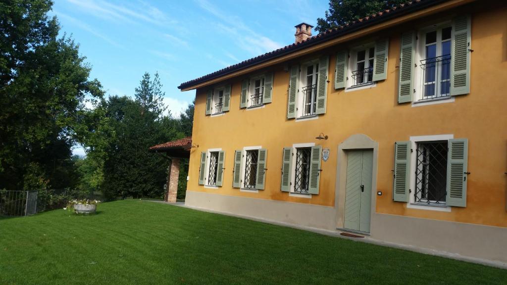 une maison avec une pelouse verte devant elle dans l'établissement Cascina Rollone, à Rocchetta Tanaro