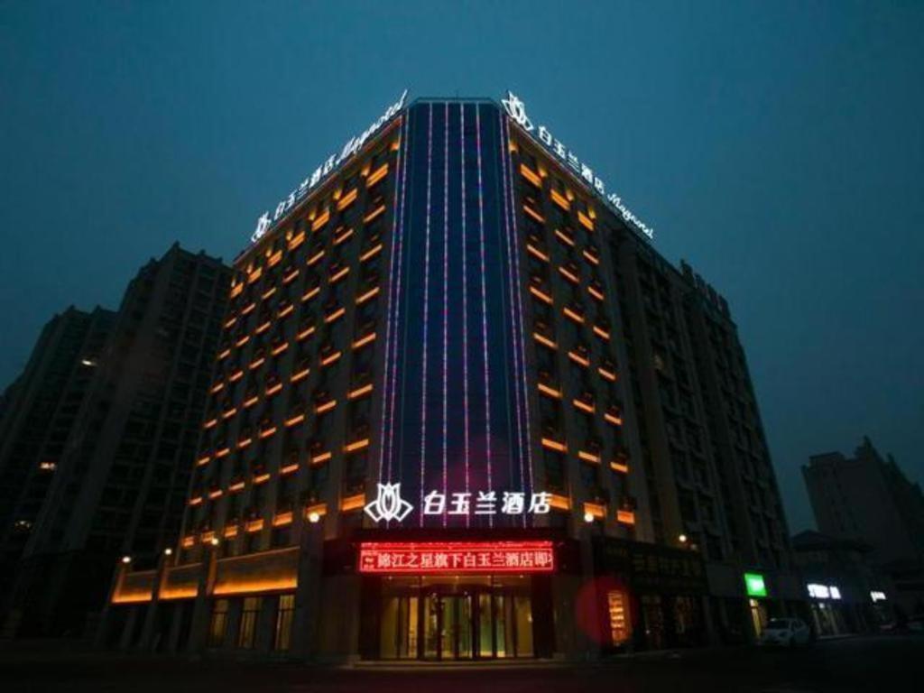 ein hohes Gebäude mit einem Schild in der Nacht in der Unterkunft Magnotel Jining Jiada in Liuxing