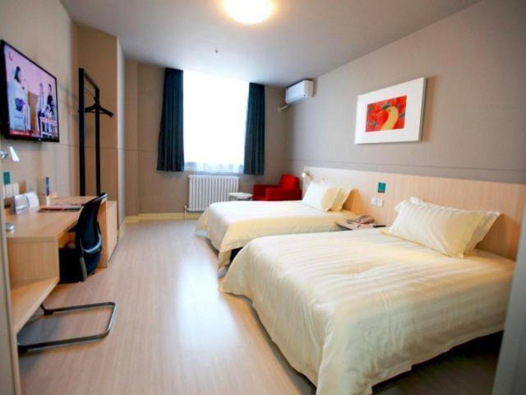 Cette chambre comprend deux lits et un bureau. dans l'établissement Jinjiang Inn Dalian Huanan Square Zhonghua Road, à Nanguanling