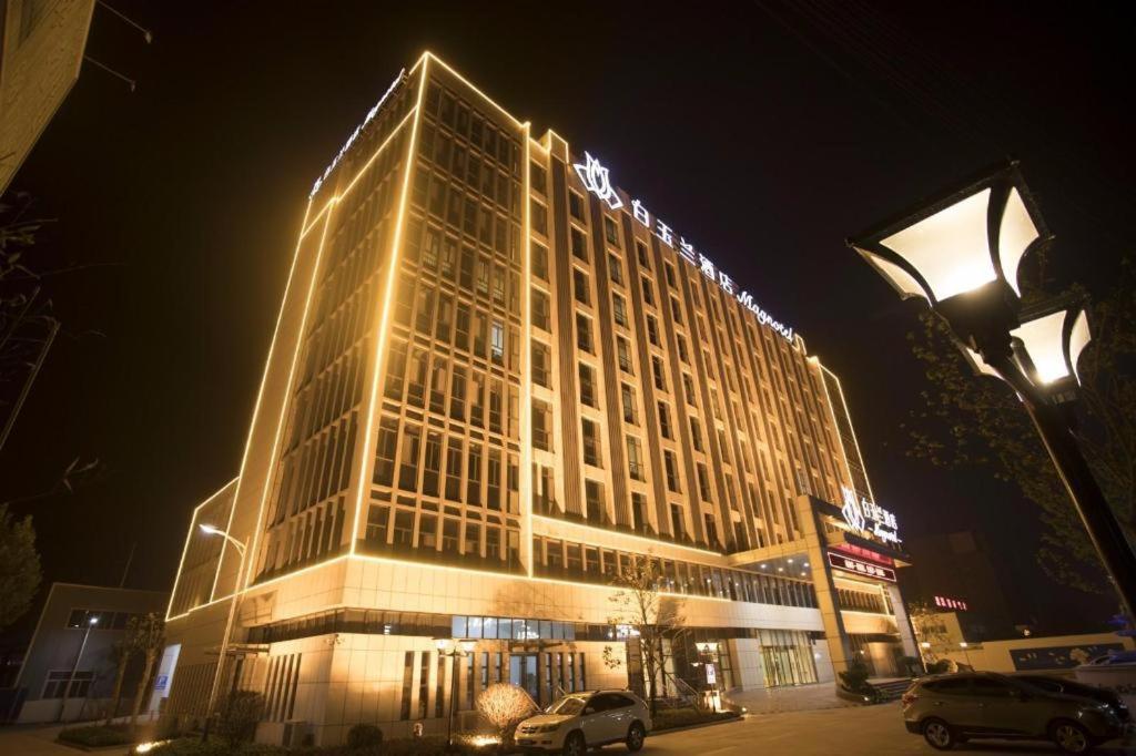 un edificio alto con luces encendidas por la noche en Magnotel Jining Jiaxiang Zengzi Avenue, en Jiaxiang
