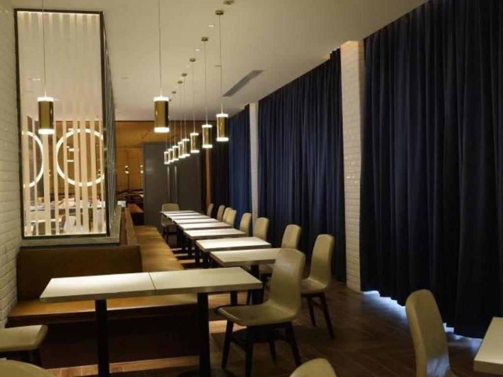 una fila de mesas y sillas en un restaurante en Jinjiang Inn Select Jiuquan Wanda Plaza en Jiuquan
