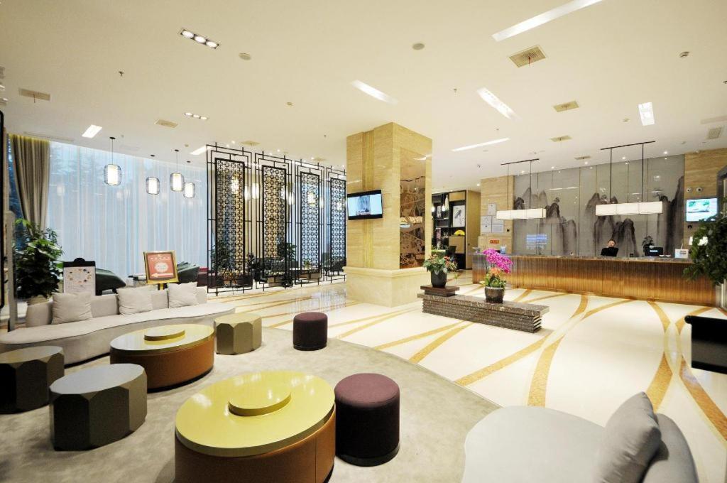 un vestíbulo con sofás y taburetes en un edificio en Metropolo Hotel Kunshan Jinying International Kun Opera Theater en Kunshan