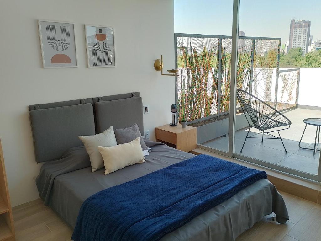1 dormitorio con 1 cama con manta azul y balcón en Onmood Roma Norte by HiHab New Opening 2024, en Ciudad de México