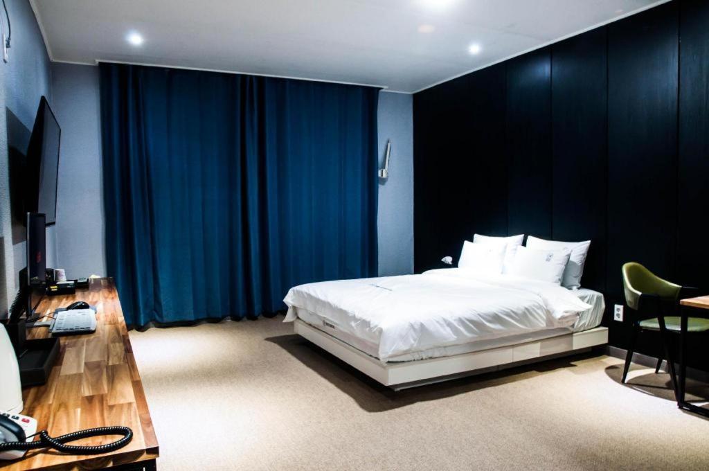een slaapkamer met een wit bed en blauwe gordijnen bij Heitz Hotel 