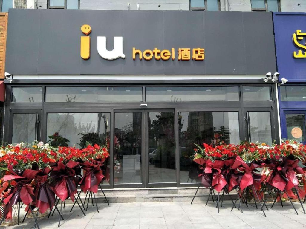 a hotel with red flowers in front of a building at IU Hotel Qingdao Golden Beach Xuejiadao Metro Station in Huangdao