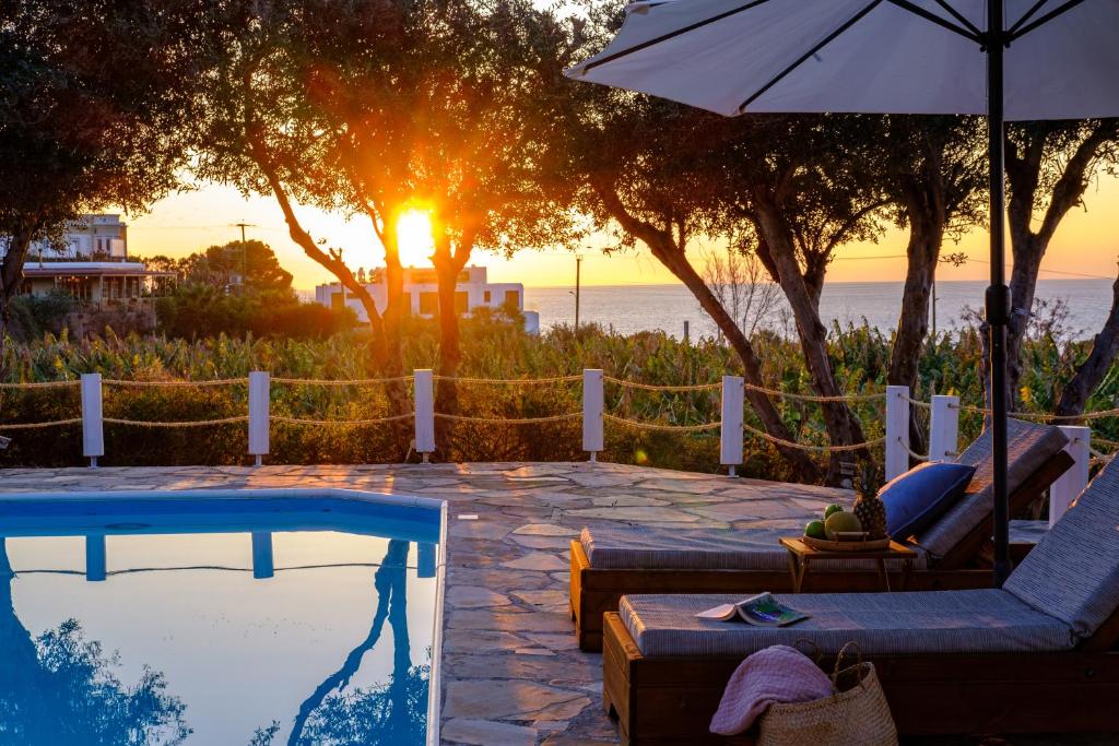 a swimming pool with an umbrella and a chair and a table at Blue Waves Villa by Nomads in Kissonerga