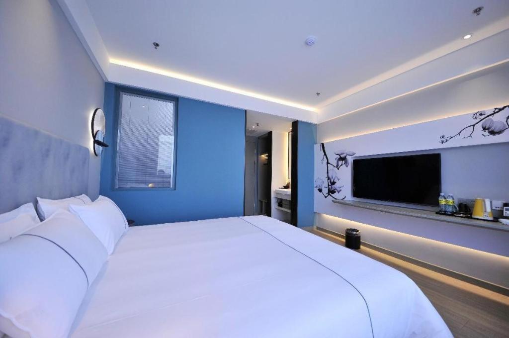 a bedroom with a large white bed with a blue wall at Magnotel Hotel Rizhao Dengta Scenic Spot Lianyungang Road in Rizhao