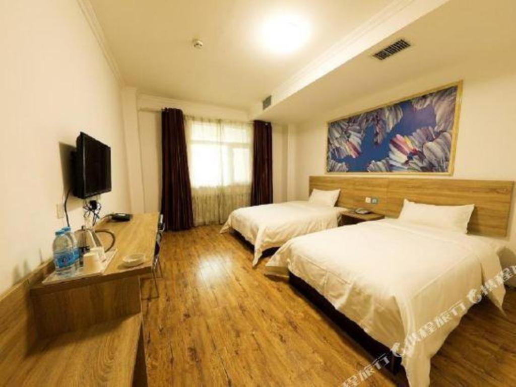 een hotelkamer met 2 bedden en een televisie bij PAI Hotel·Hami Yingbin Avenue Airport in Hami