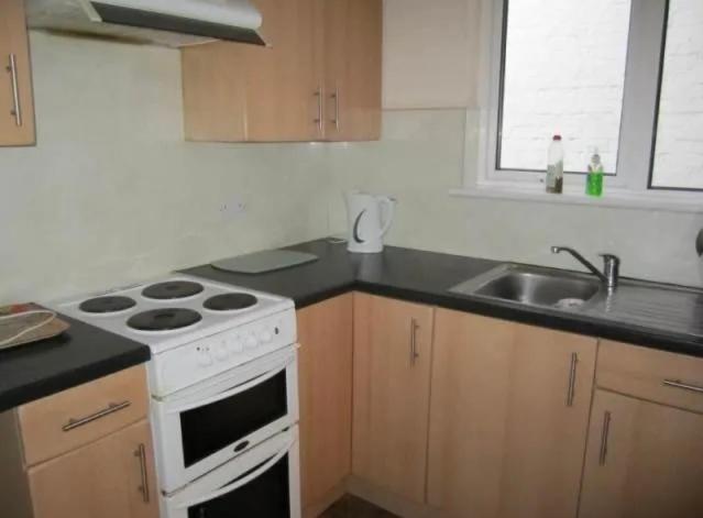 uma cozinha com um fogão branco e um lavatório em Durley house em Alphington