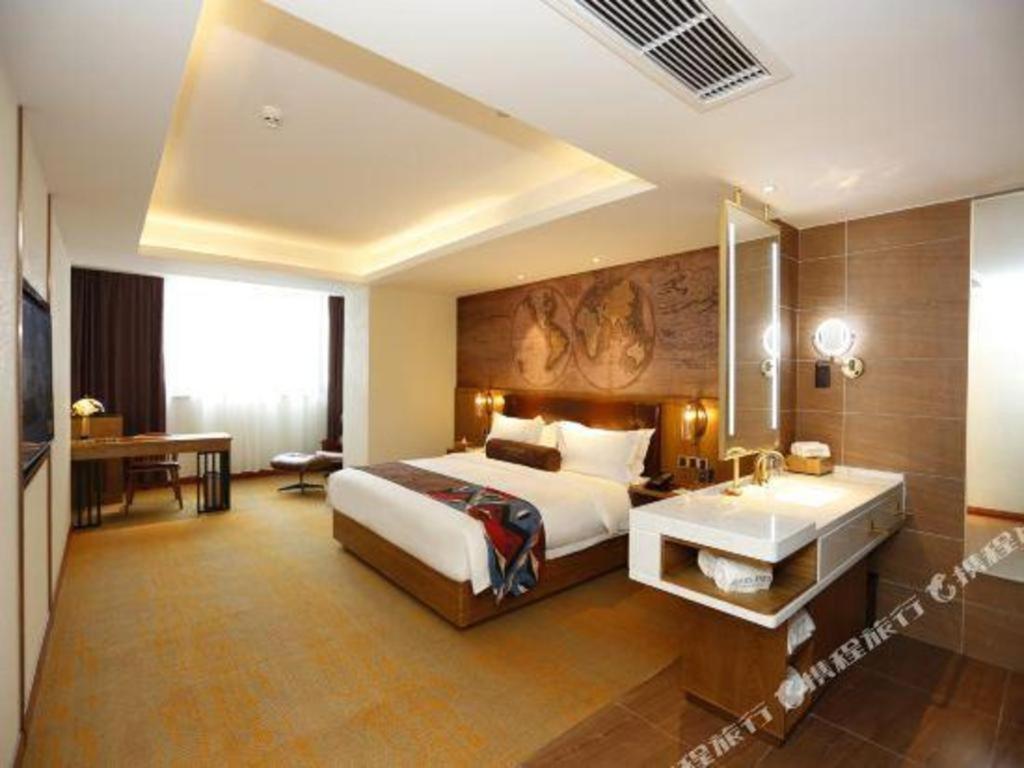 a hotel room with a bed and a sink in it at James Joyce Coffetel Tianjin Development 3rd Street MSD in Binhai