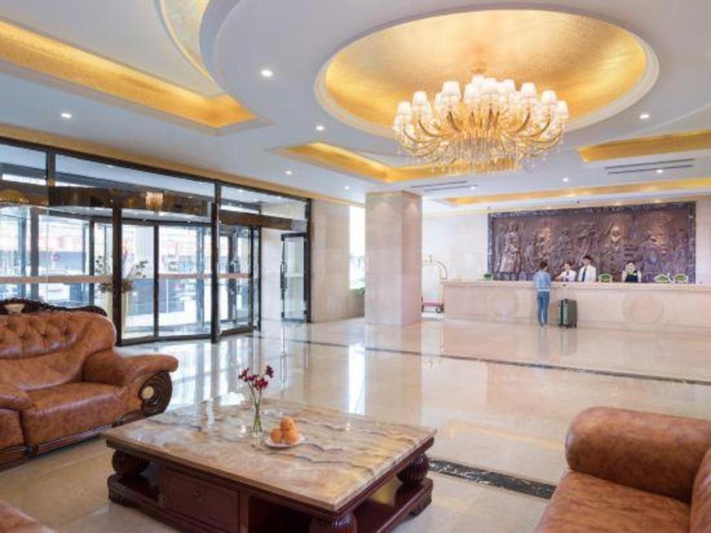 eine große Lobby mit einem Kronleuchter und einem Tisch in der Unterkunft Vienna Hotel Tongliao Ke'erqin in Tongliao