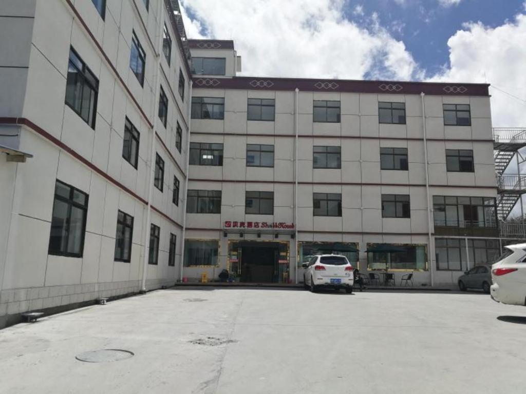 duży budynek z samochodem zaparkowanym przed nim w obiekcie Shell Linzhi Bayi Area G318 Shuangyong Road Hotel w Nyingchi